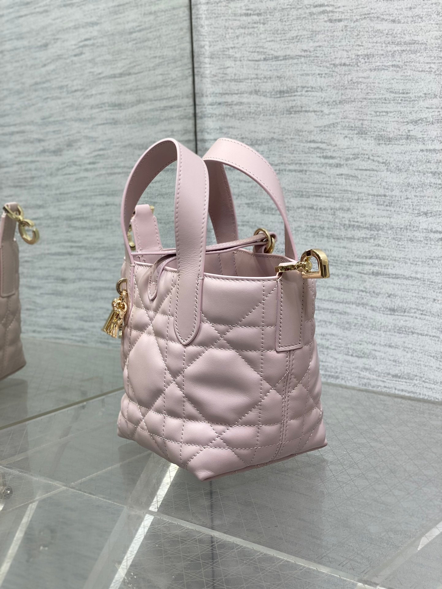 Pink Dior quilted handbag with side view, dual handles, and gold top clasp