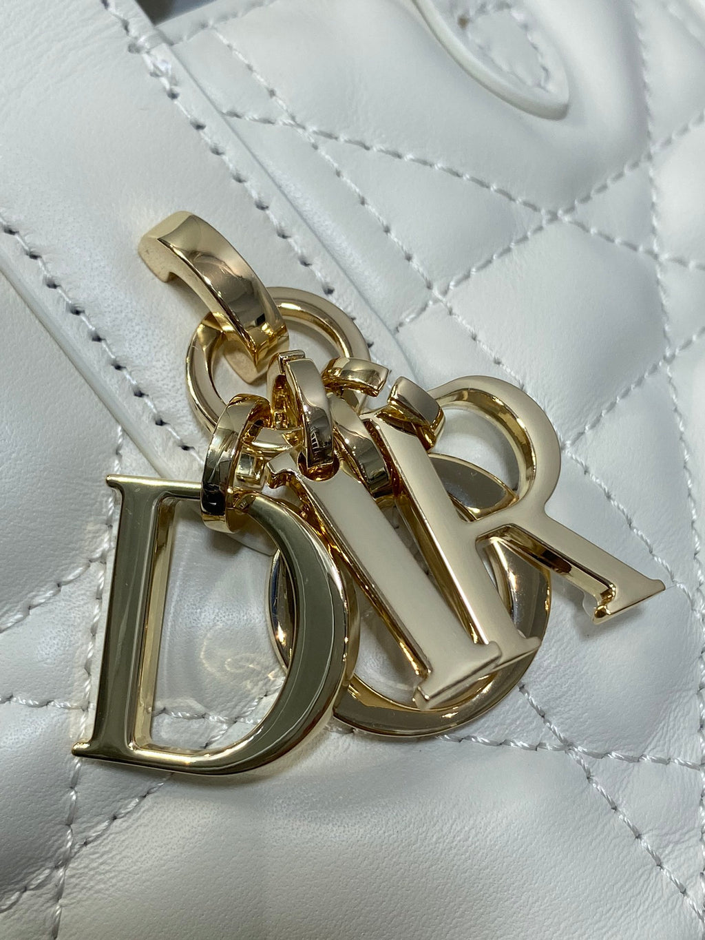 Dior charm detail on quilted white leather bag, gold clasp and hardware