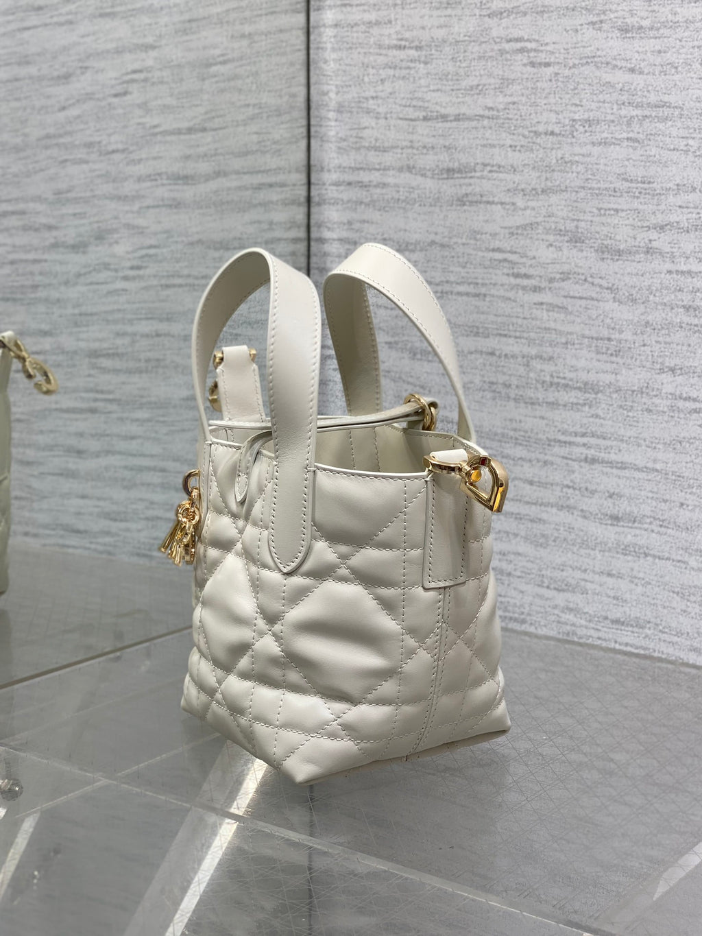 Dior quilted mini tote bag side view, white leather, gold charm and shoulder strap