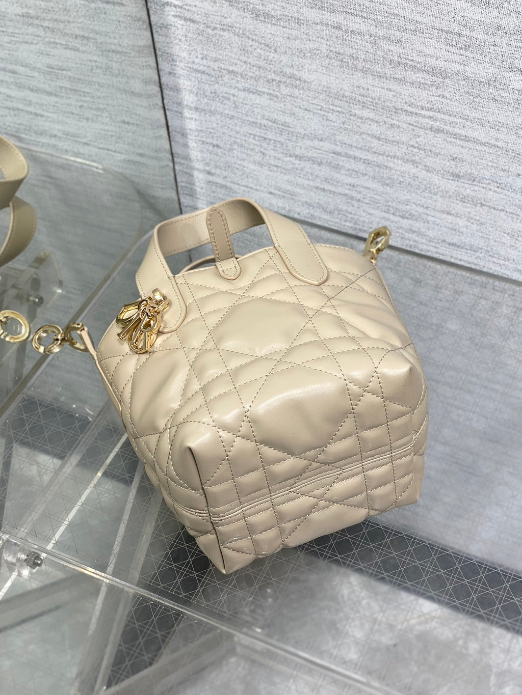 Dior quilted mini handbag with rounded shape and top handles, gold charm