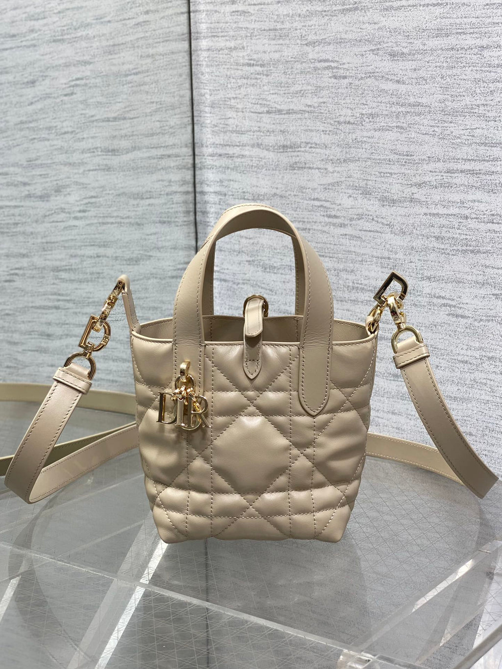 Dior quilted mini handbag with shoulder strap, gold hardware, and front charm