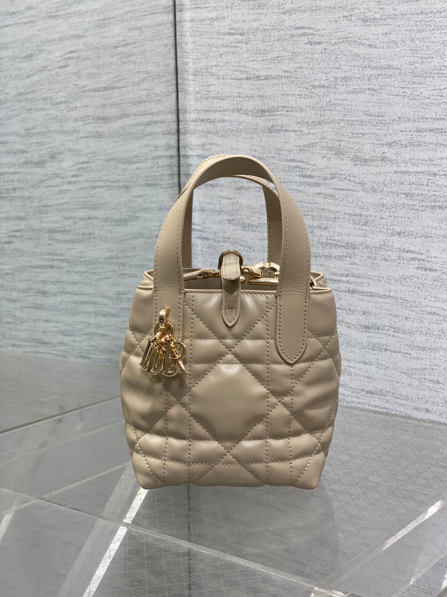 Dior quilted mini handbag with top handles, gold hardware, and charm detail