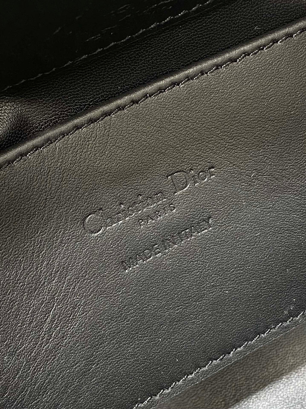 Black leather Dior-embossed handbag detail with stitched edge