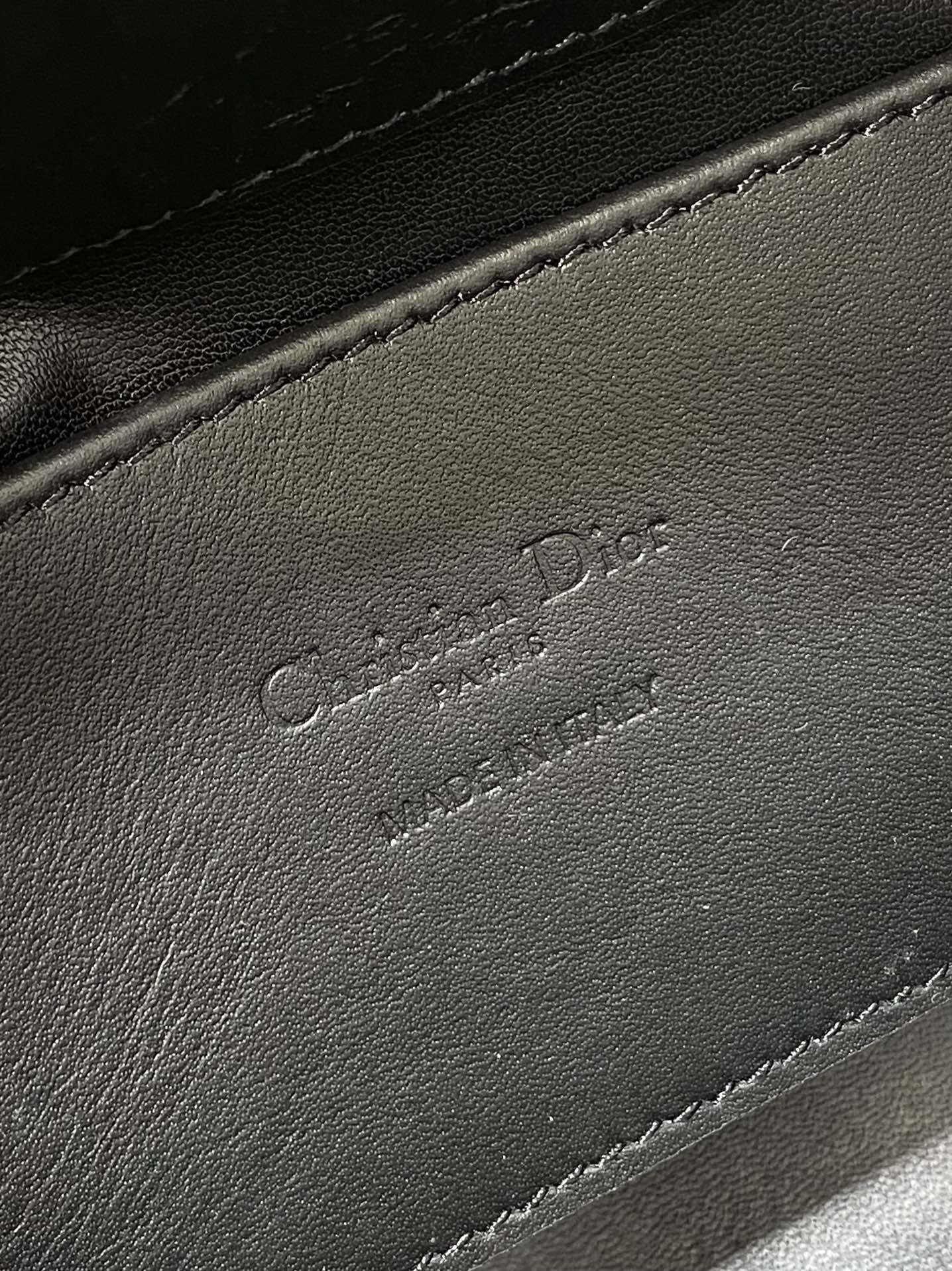 Black leather Dior-embossed handbag detail with stitched edge