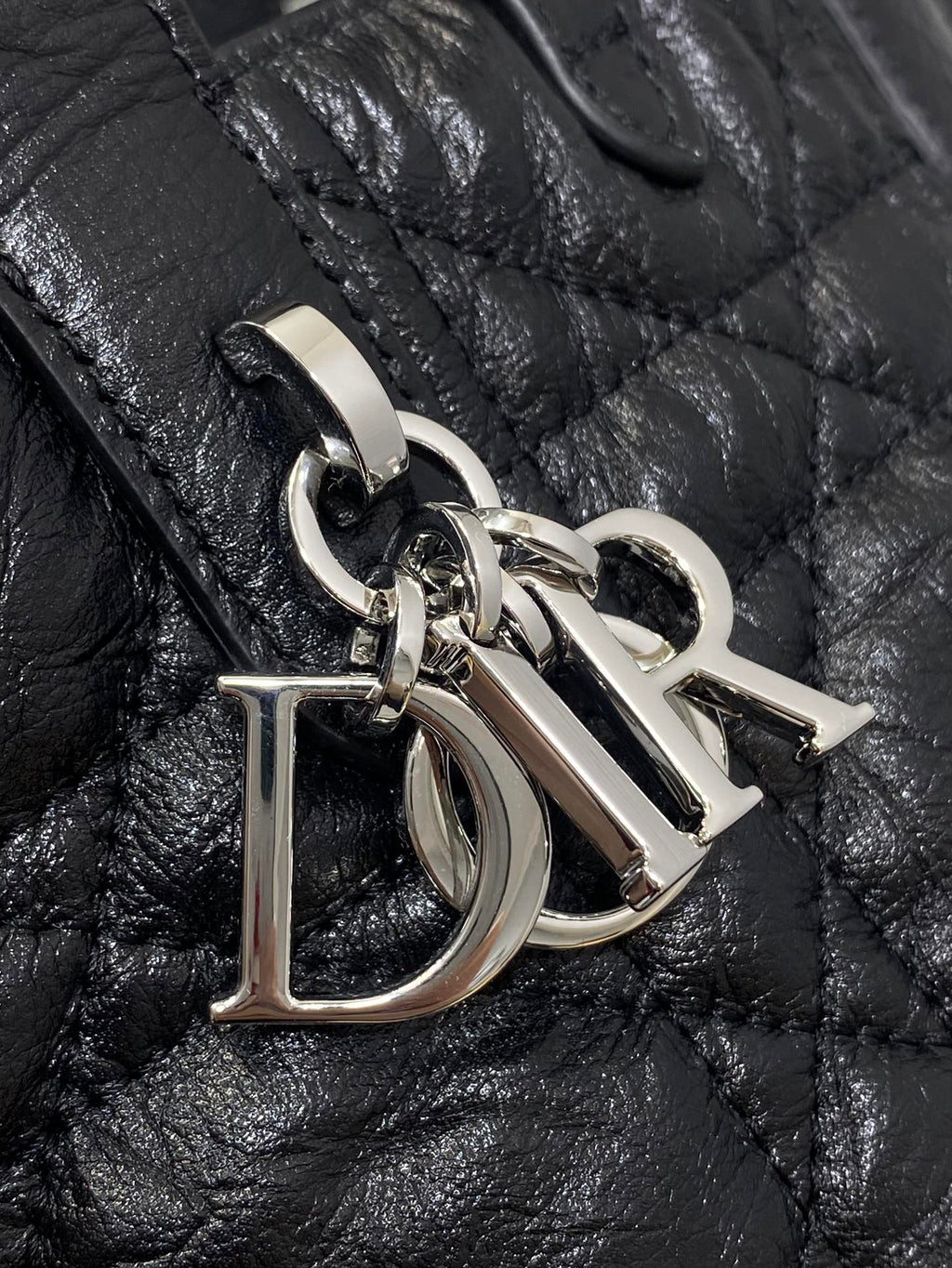 Metal D-shaped charm on black quilted leather handbag