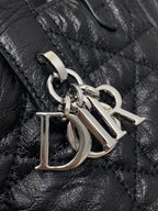 Metal D-shaped charm on black quilted leather handbag