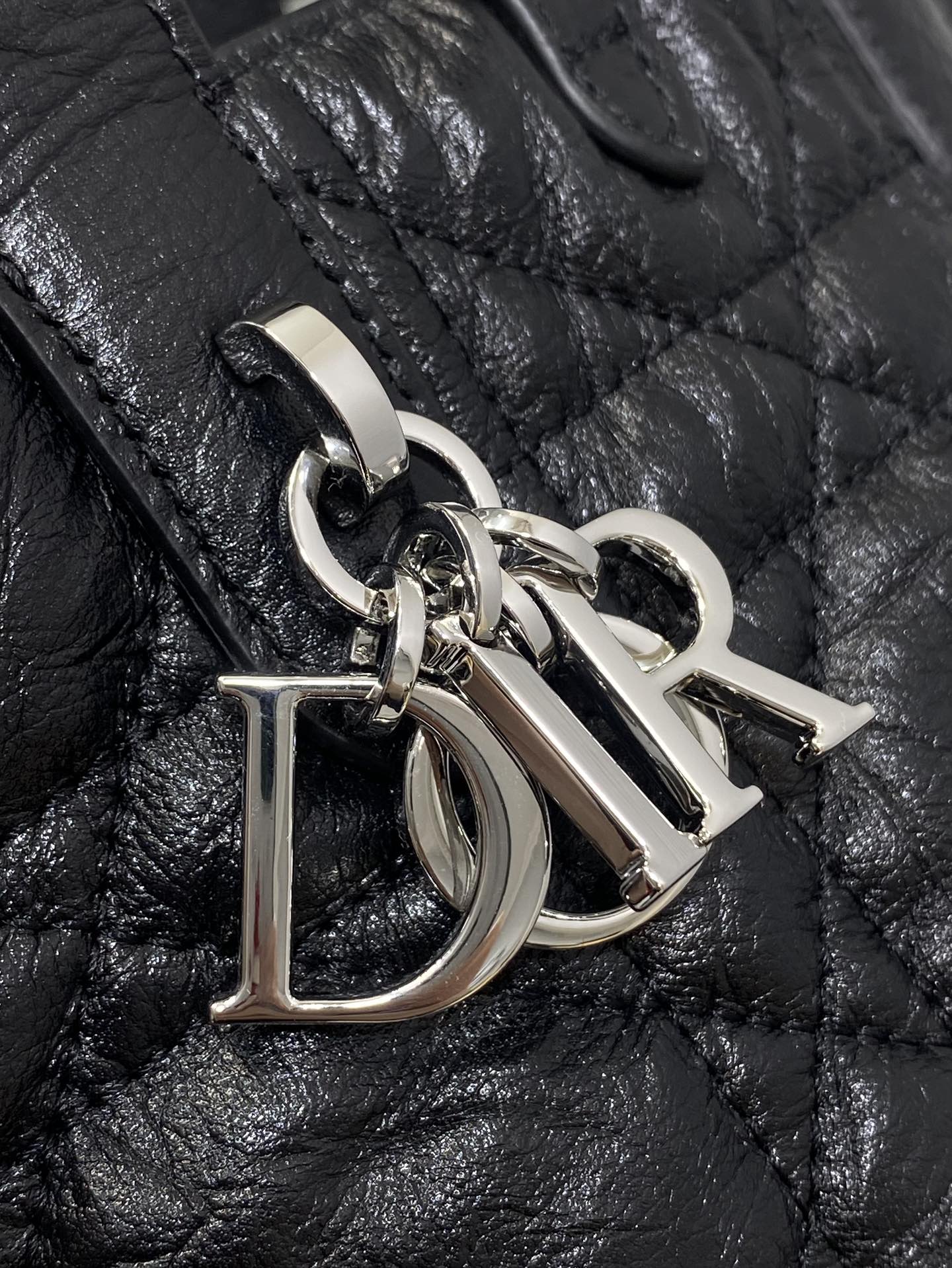 Metal D-shaped charm on black quilted leather handbag