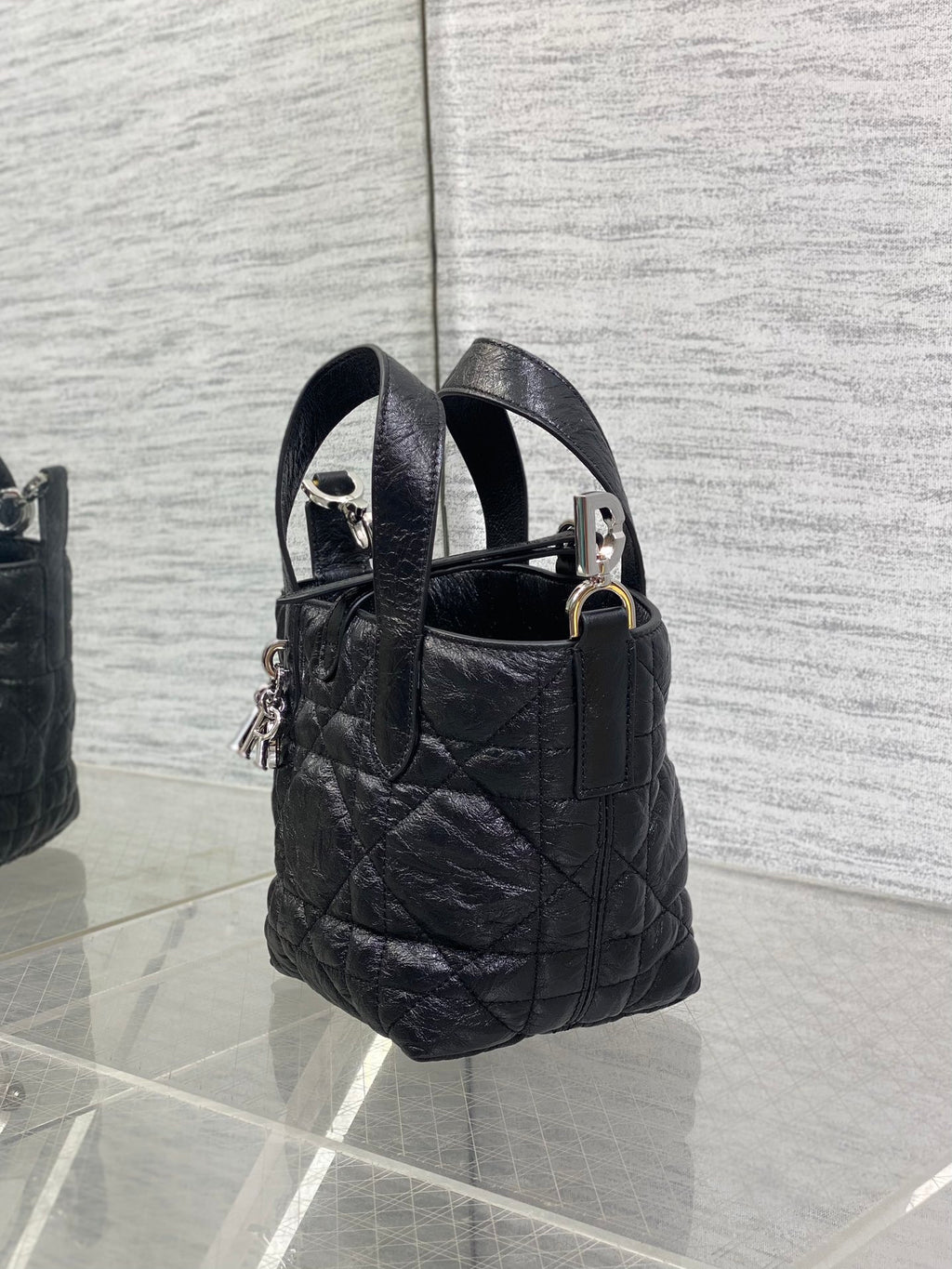 Black quilted mini handbag with two top handles and hanging charm