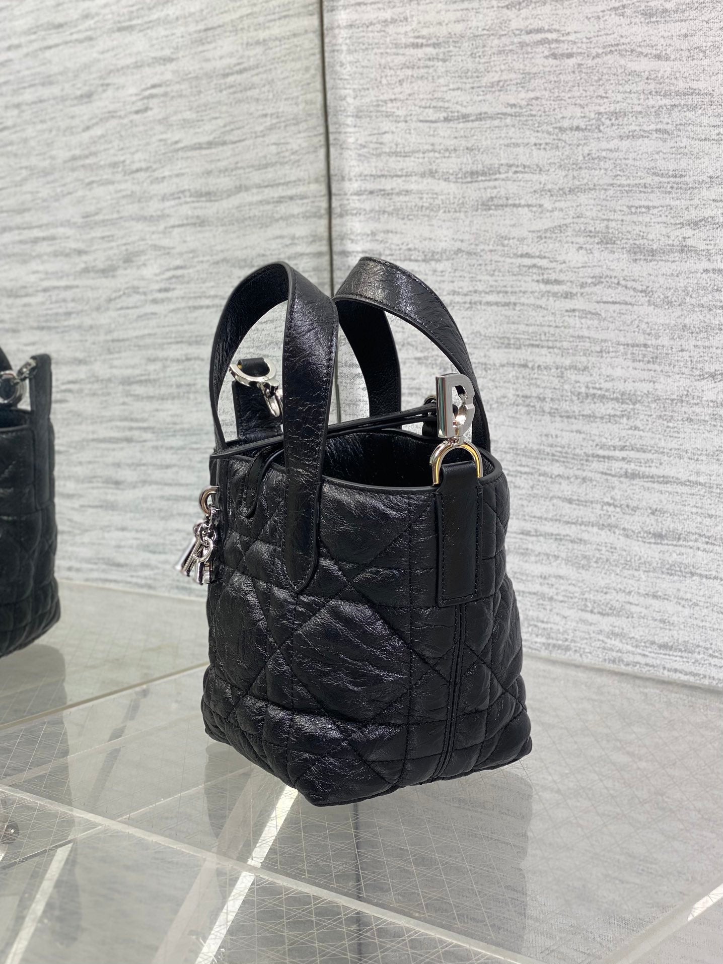 Black quilted mini handbag with two top handles and hanging charm