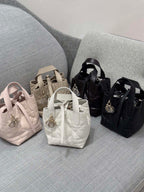 Dior bag mini totes on display: light pink, white, beige, and black with charms