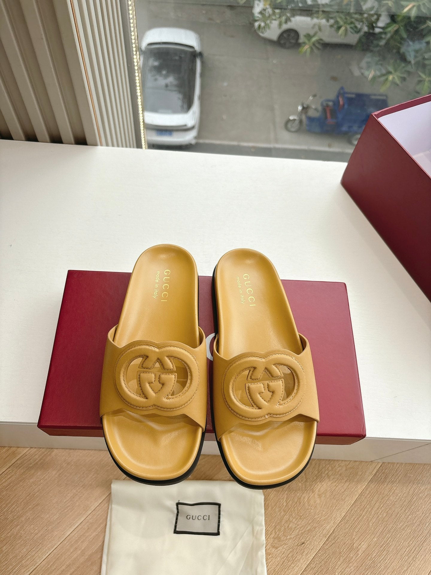 Gold Gucci slide sandals pair view with interlocking G logo; dust bag