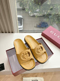 Gold Gucci slide sandals with embossed interlocking G logo on straps