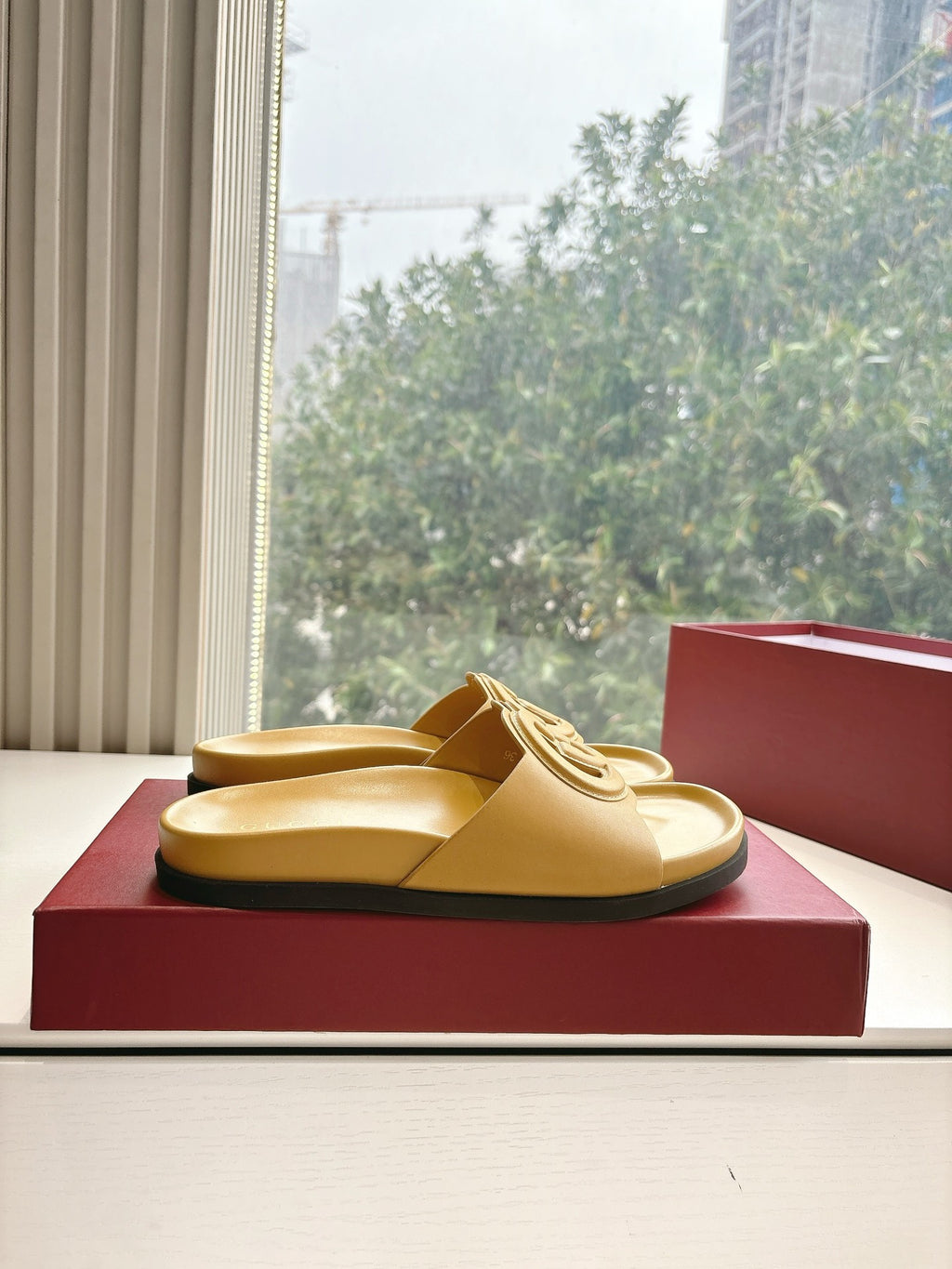 Gold Gucci slide sandals resting on box, interlocking G strap