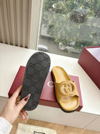 Gold Gucci slide sandals with black Gucci monogram dust bag