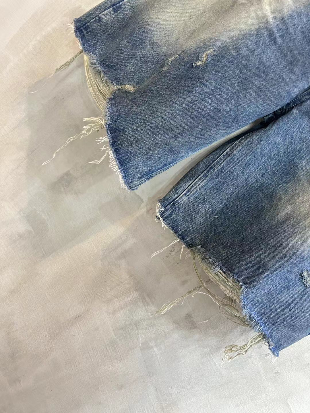 Denim shorts corner view with raw frayed hem and distressed fabric