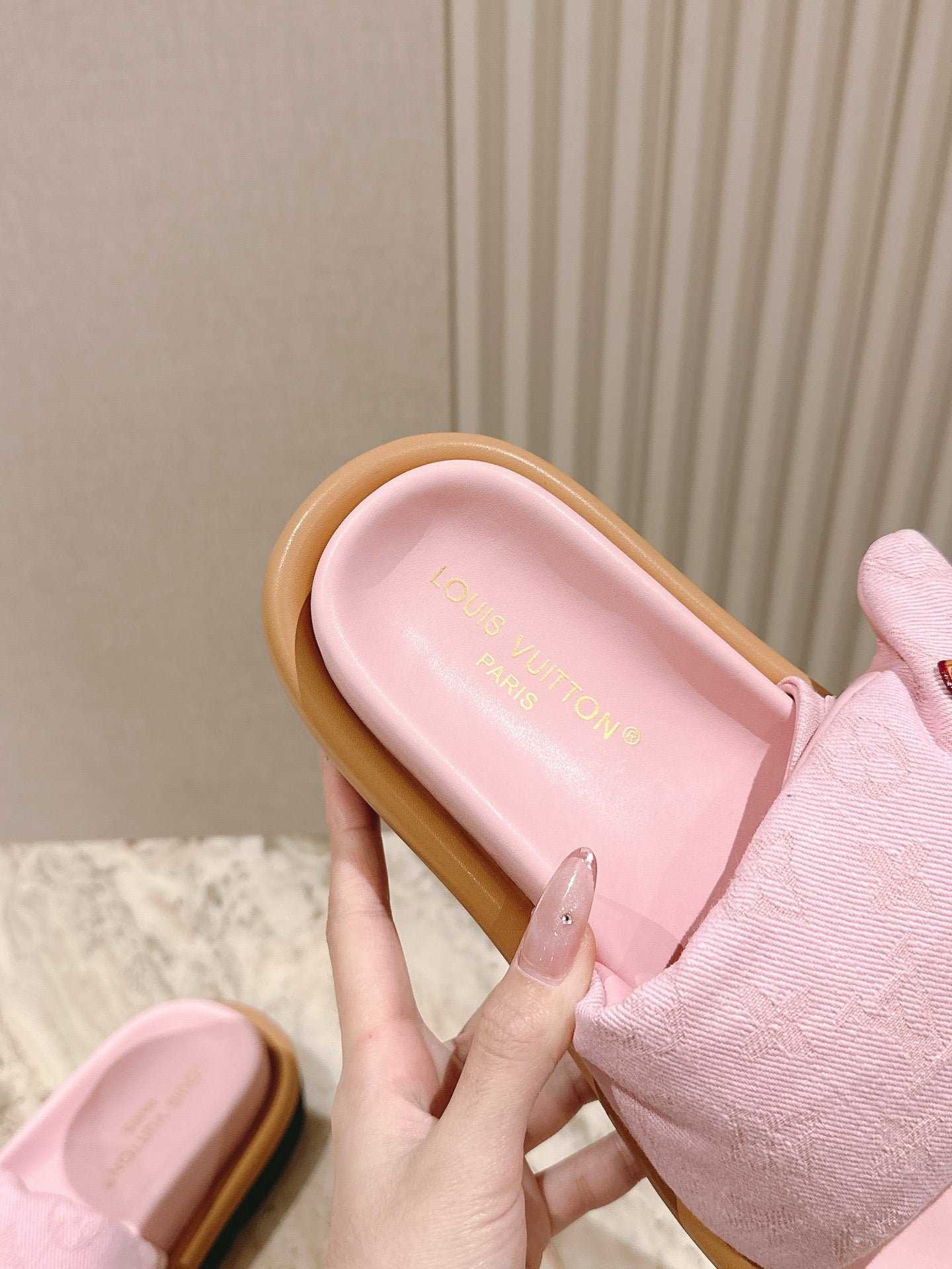 Louis Vuitton pink slide sandal close-up, pink footbed and tan rubber strap edge