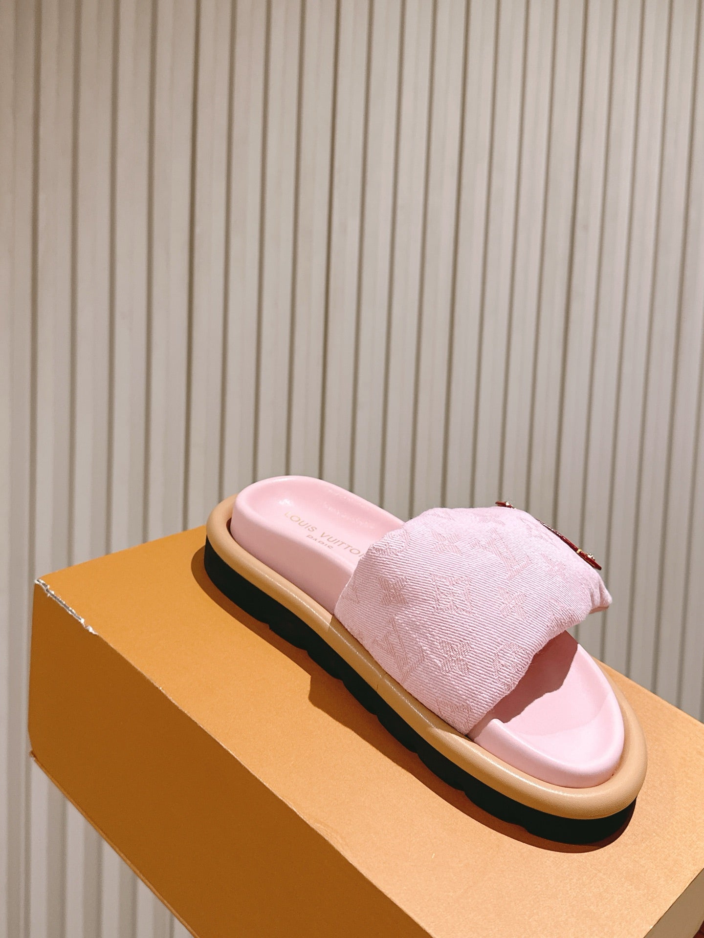 Louis Vuitton pink slide sandals resting on a box, tan sole and gold-tone strap buckle