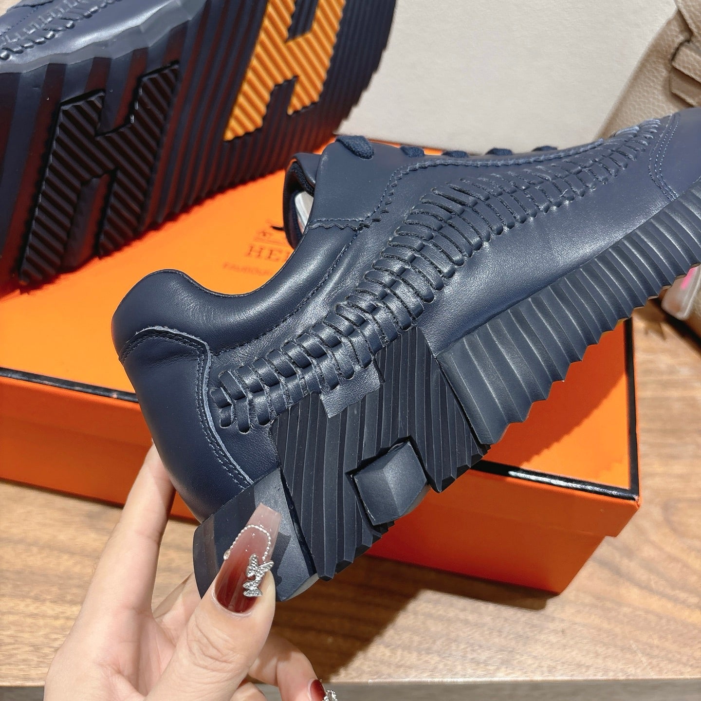 Hermes unisex dark blue sneaker close-up, lace-up upper with chunky ribbed sole