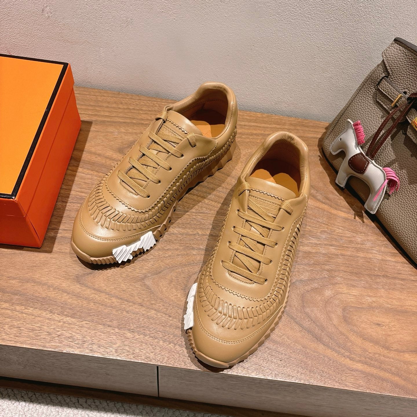 Beige lace-up sneakers with textured panels, stitched details, and chunky tread
