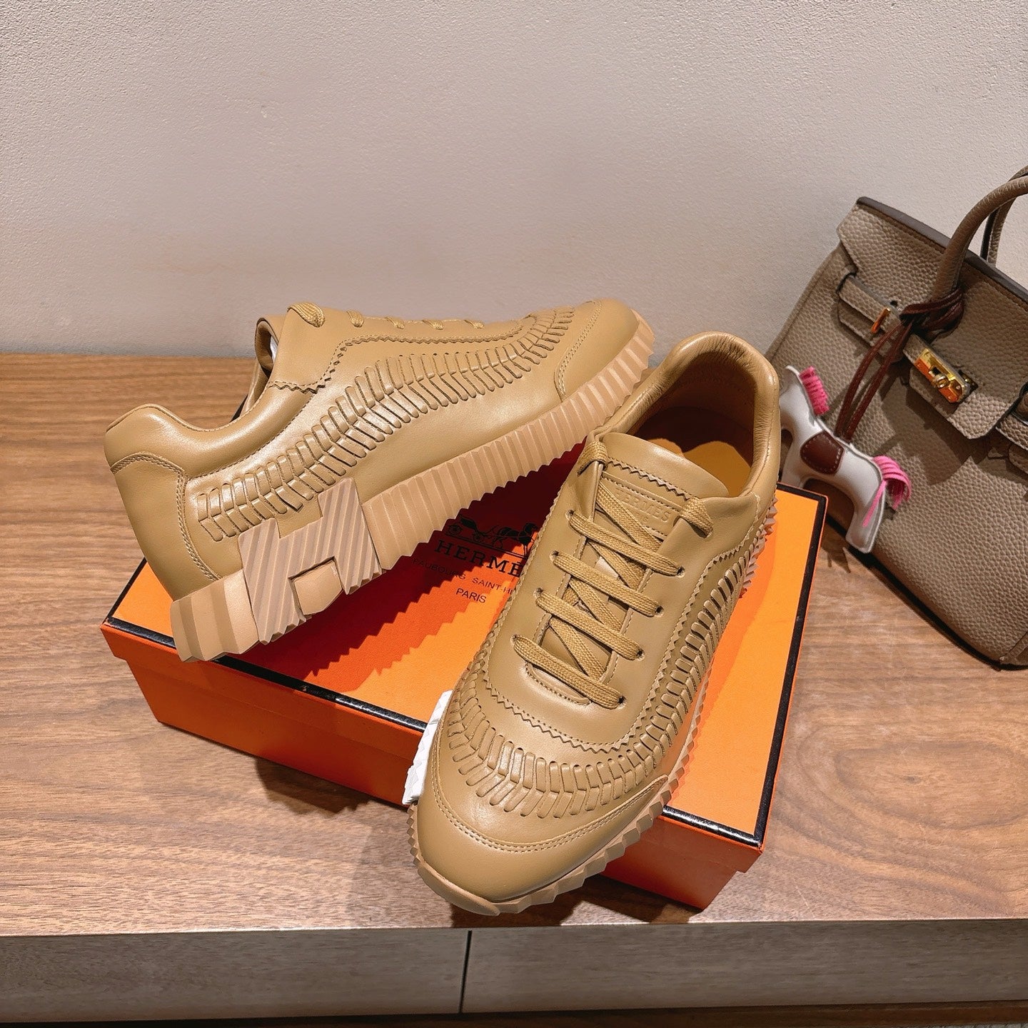 Beige sneaker with lace-up front, raised seam detailing, and thick striped sole