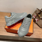 Gray lace-up sneakers with textured strap-like seams and thick treaded sole.