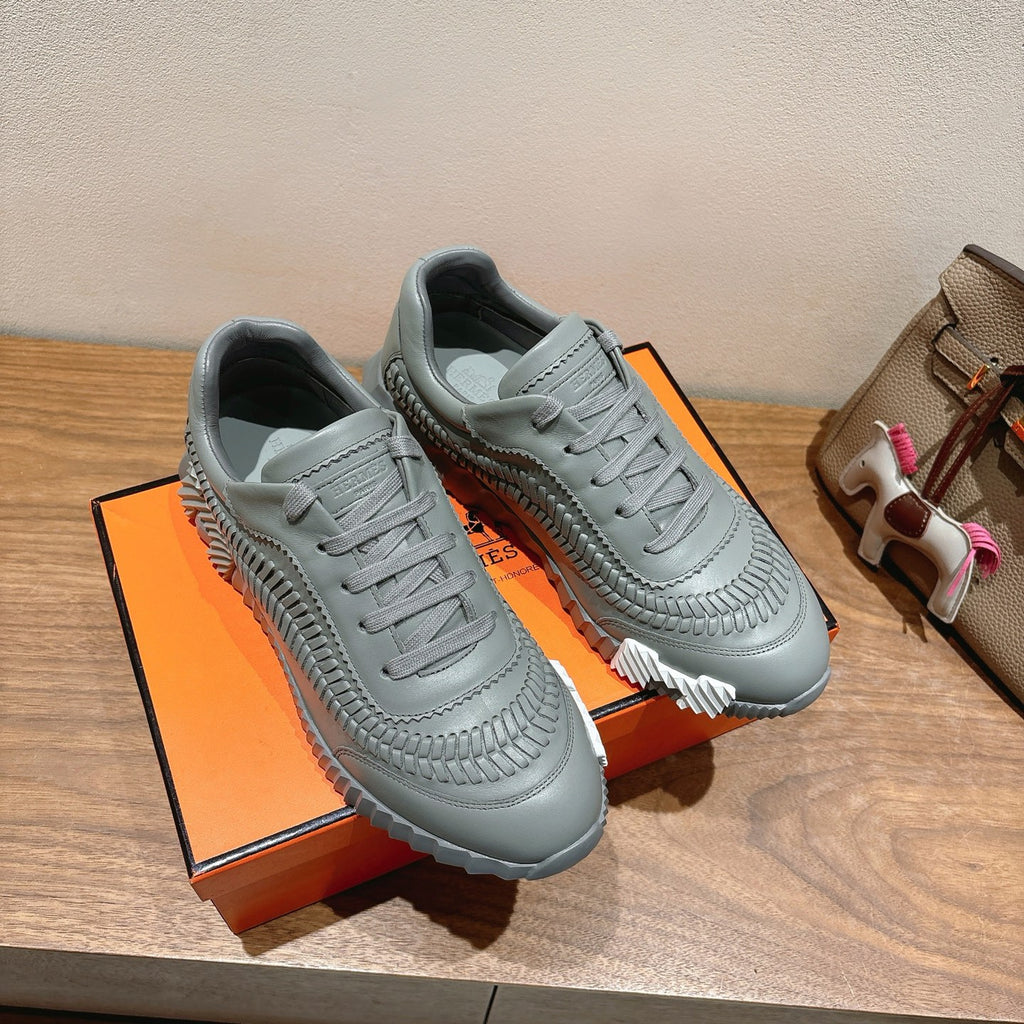 Gray lace-up sneakers on box, with quilted toe pattern and chunky white outsole.