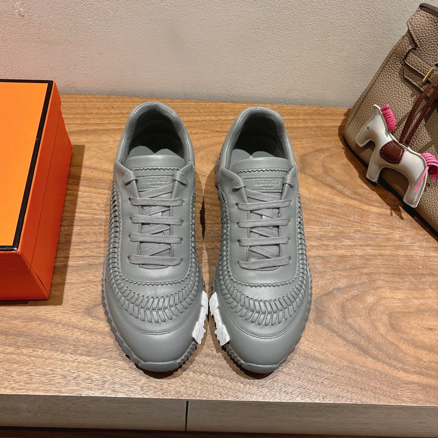 Gray lace-up sneakers with braided toe detail and rugged white sole.