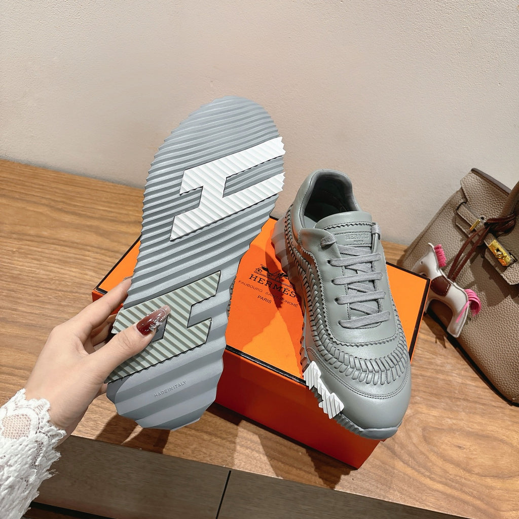 Gray lace-up sneaker outsole with thick tread and side panel seam details.