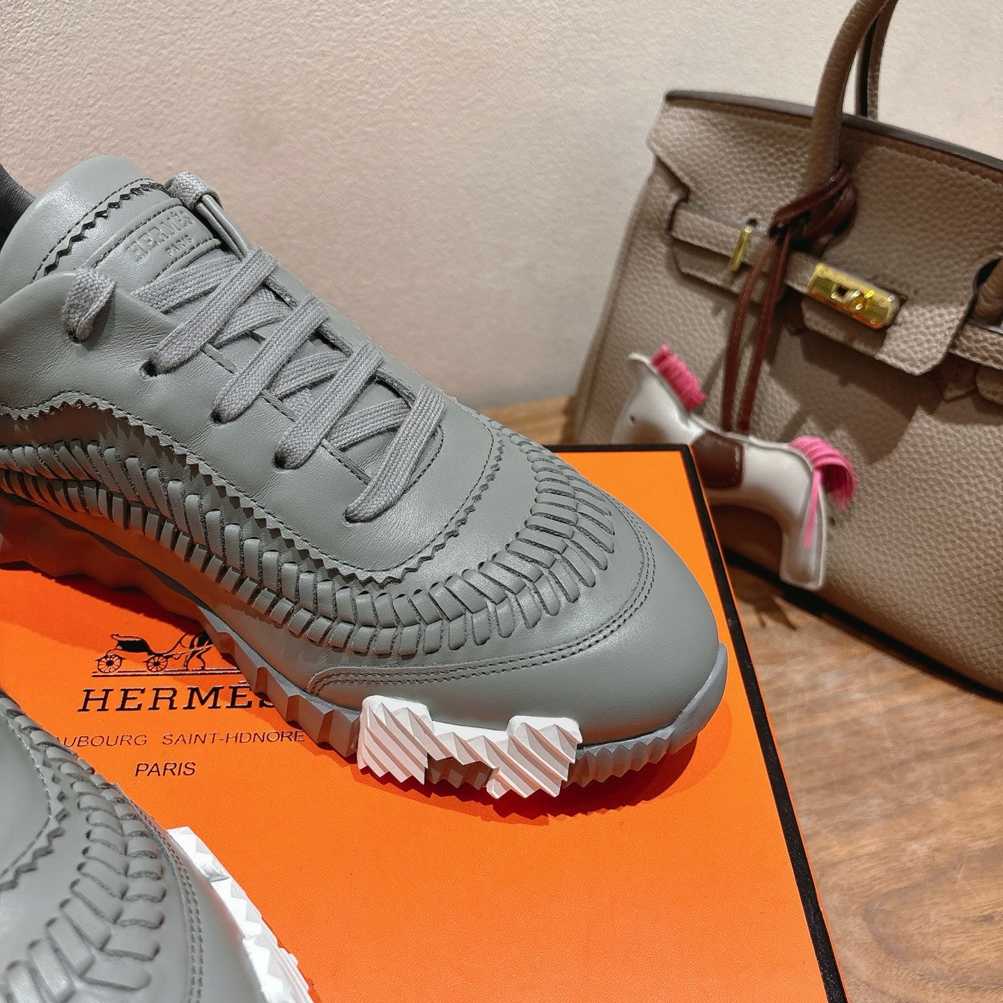 Close-up of gray lace-up sneaker upper with detailed toe stitching and tread sole.