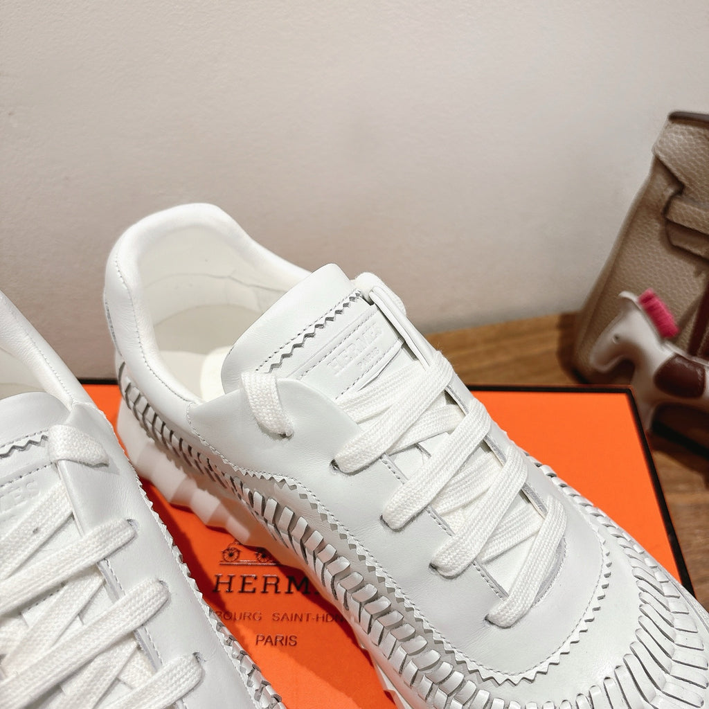 Hermes unisex white sneaker close-up, lace eyelets and ribbed side trim