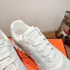 Hermes unisex white sneaker close-up, lace eyelets and ribbed side trim