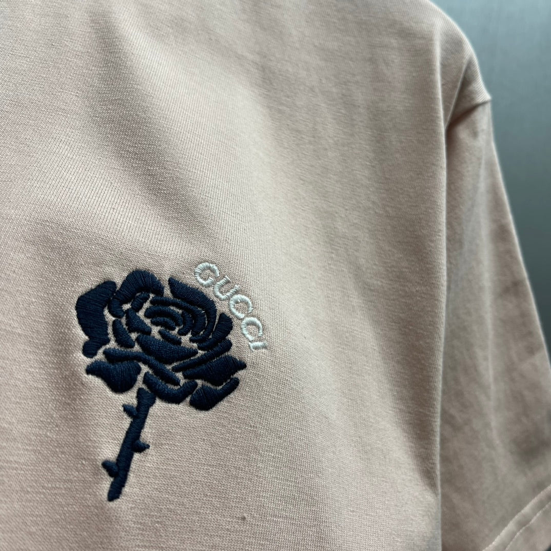 Light pink T-shirt sleeve with dark blue rose embroidery and light text