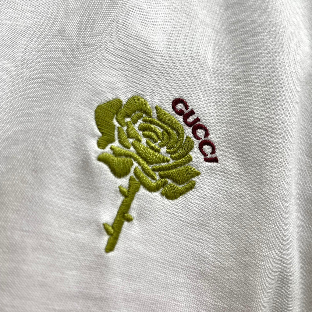 Close-up of green rose and red Gucci embroidery on white T-shirt