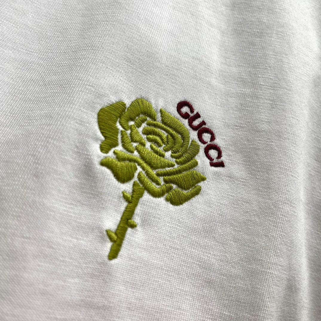 Close-up of green rose and red Gucci embroidery on white T-shirt