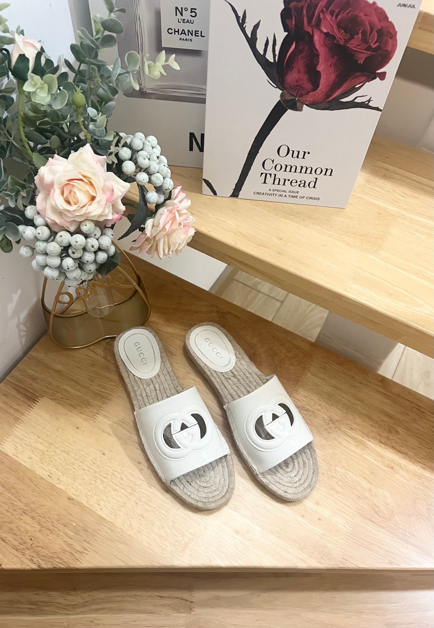 Pair of white Gucci slide sandals with black logo cutout and jute espadrille sole