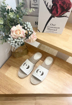 Gucci white slide sandals with logo strap and woven jute footbed, pair view.
