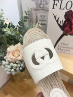 Gucci white leather slide sandal with cutout logo on woven jute sole, close-up.