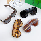 Assorted sunglasses laid flat, with dark and brown lenses, gold-tone side bars