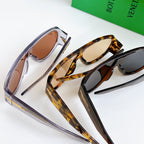 Pair of sunglasses with clear frame and tortoise frame, side gold-tone bars