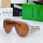 Clear-framed sunglasses with warm brown lenses and gold-tone side bar