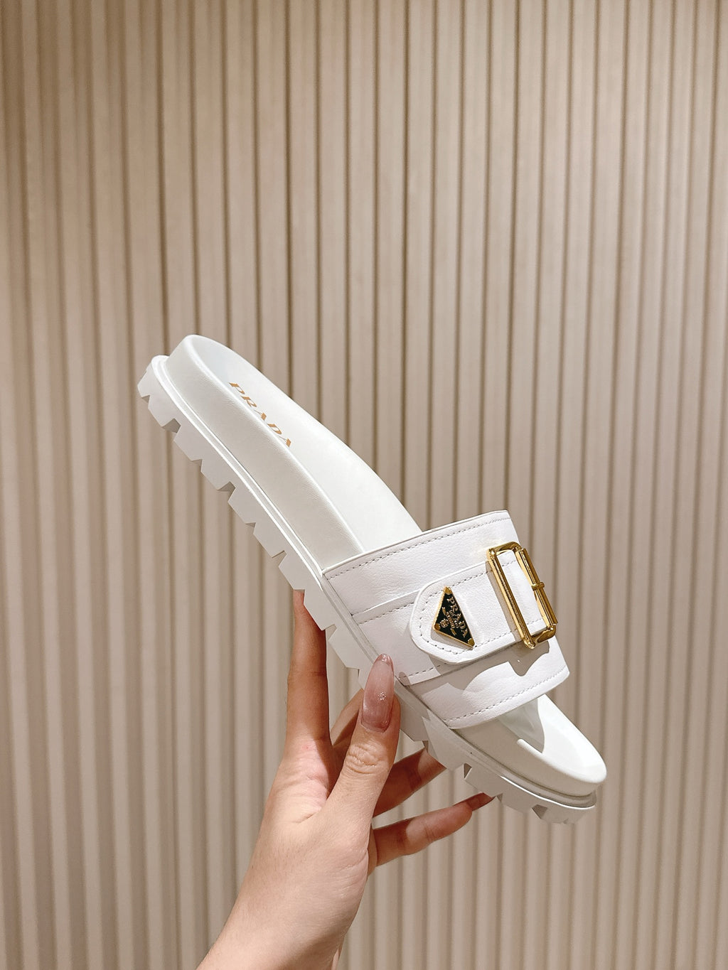 White Prada unisex slide sandals with gold buckle detail and tread sole