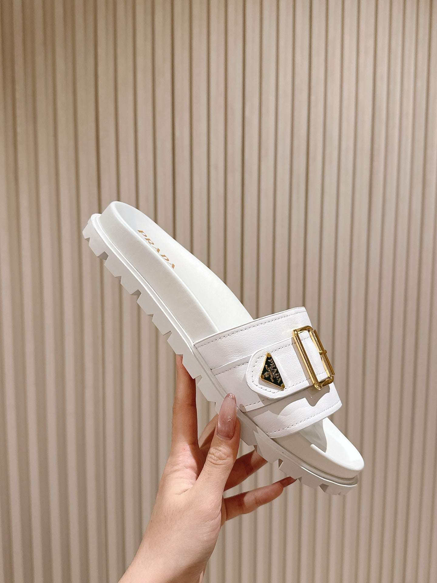 White Prada unisex slide sandals with gold buckle detail and tread sole