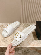 White Prada unisex slide sandals with gold buckle strap and thick tread sole