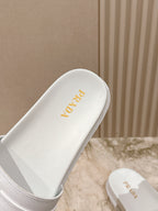 White Prada slide sandal with gold logo on footbed and side strap