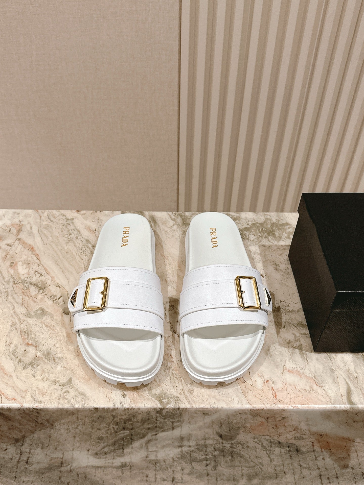 White Prada unisex slide sandals with gold square buckle and chunky sole