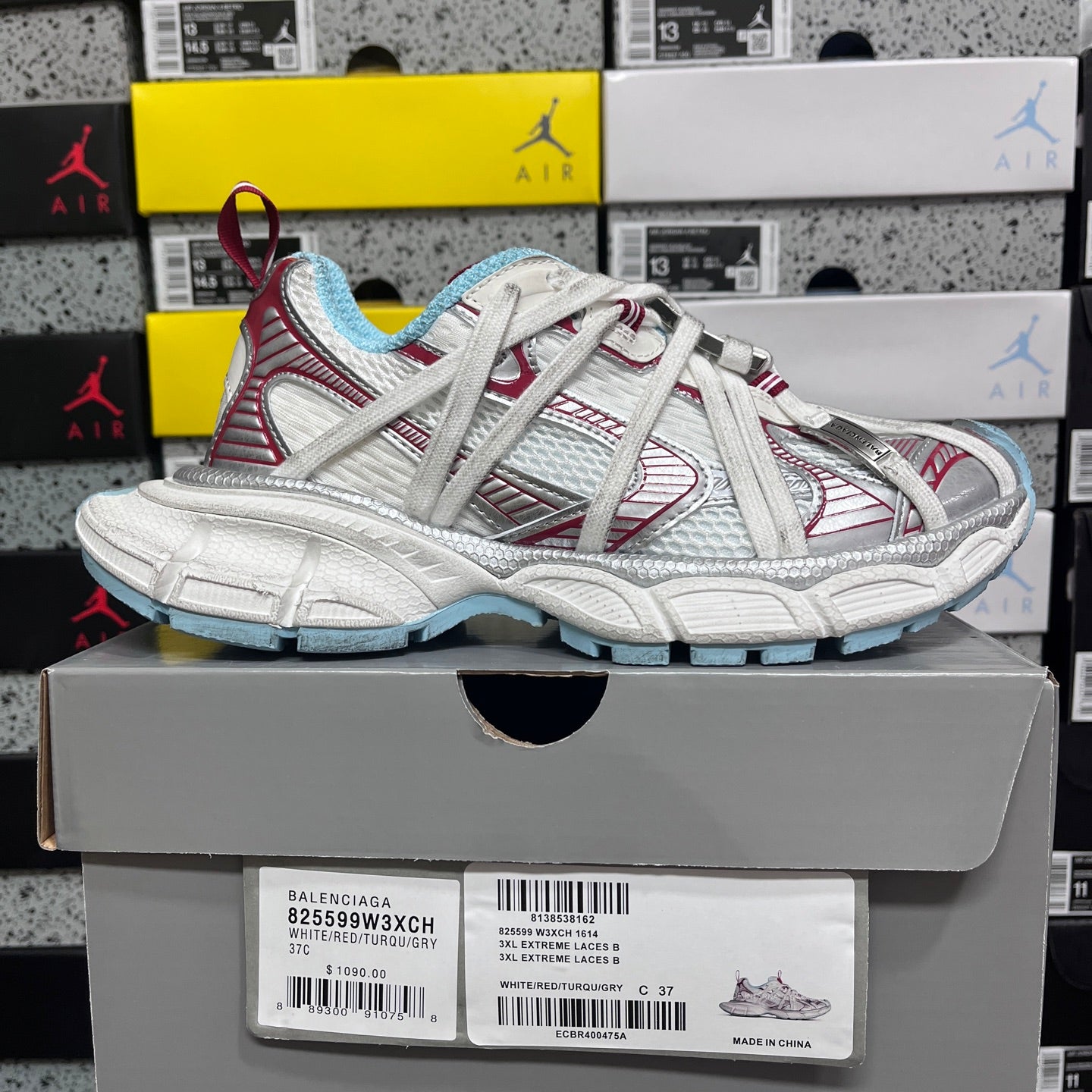 White Balenciaga sneaker with red panel lines and light blue outsole, shown on box