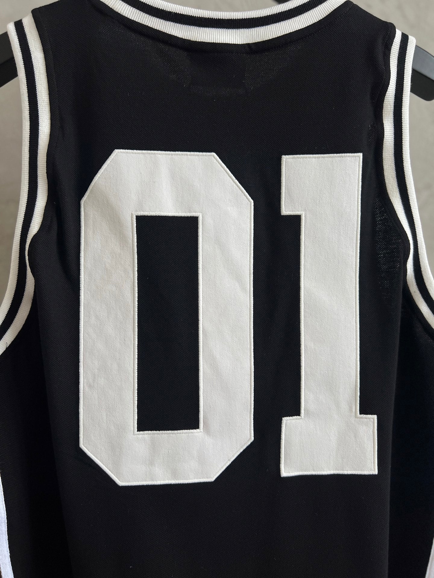 Black basketball jersey close-up with large white 01 number applique