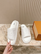 White monogram slide sandals with embossed pattern and open toe