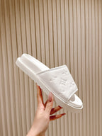 White slide sandals with embossed monogram strap and open-toe design