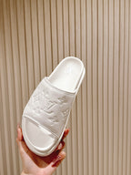 White slide sandals with embossed monogram on strap and contoured footbed